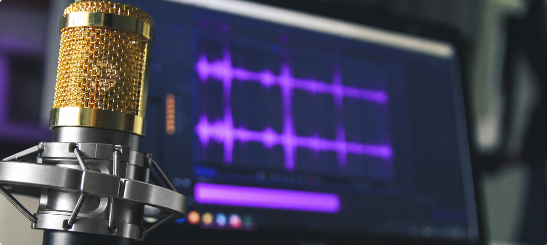 Gold studio condenser microphone in a silver shock mount with purple waveforms displayed on a computer screen.