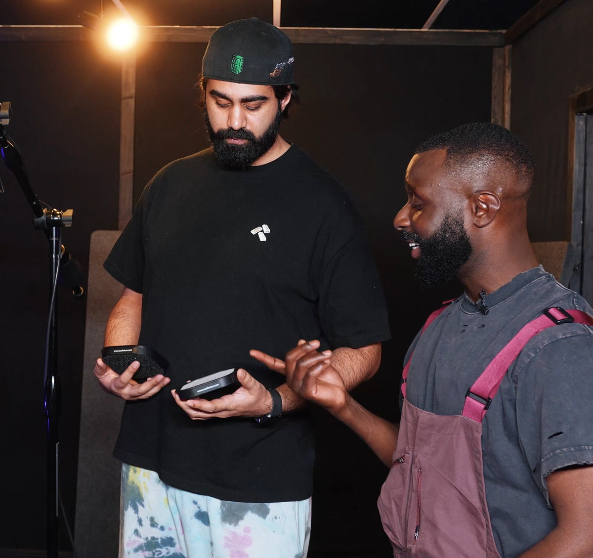 Two men interacting with Pop Shield pop filter in a studio setting