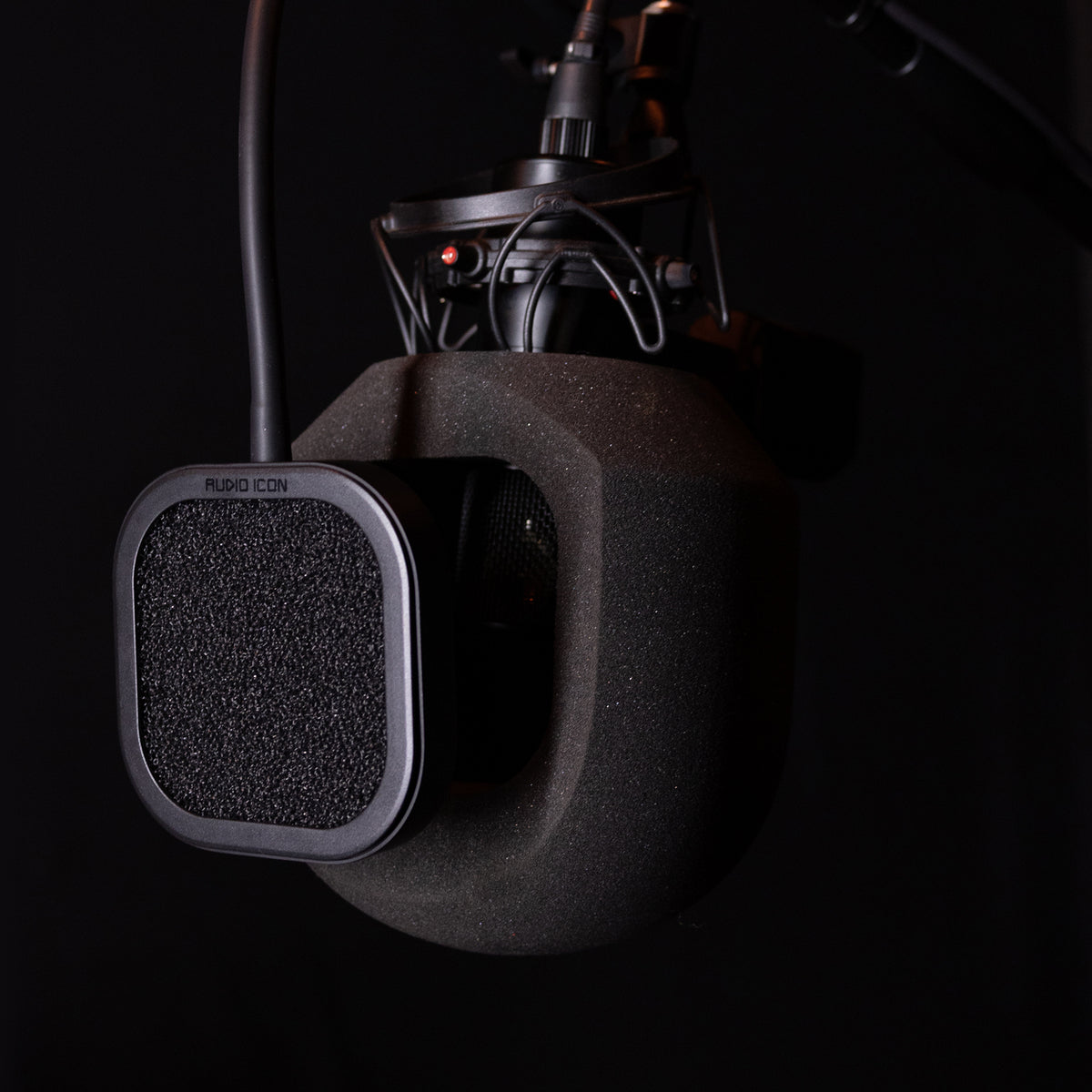 Close-up of a SoundBox microphone Isolation booth with a pop filter on a dark background