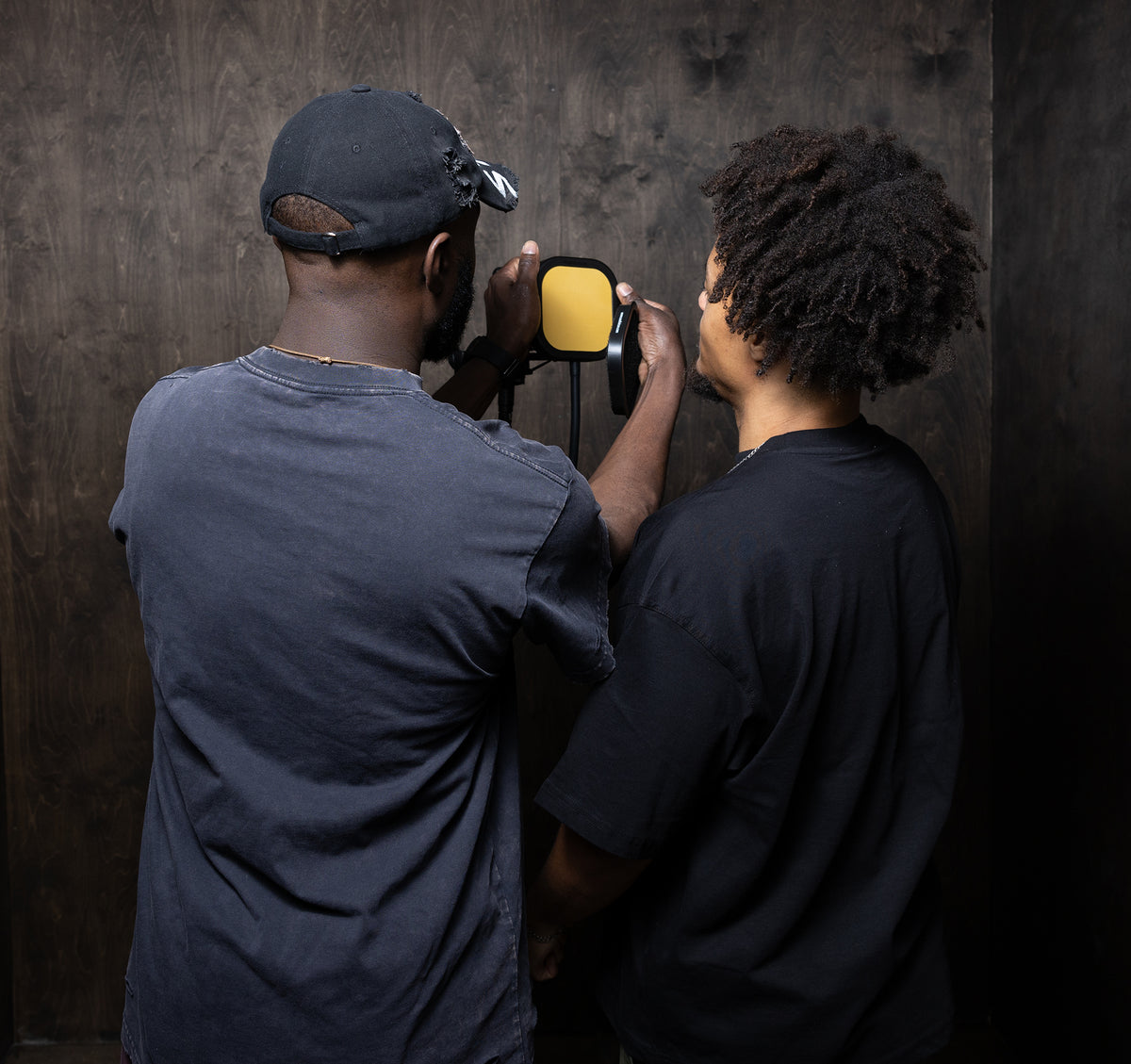 Two people holding a yellow pop shield on the flex pro against a dark background