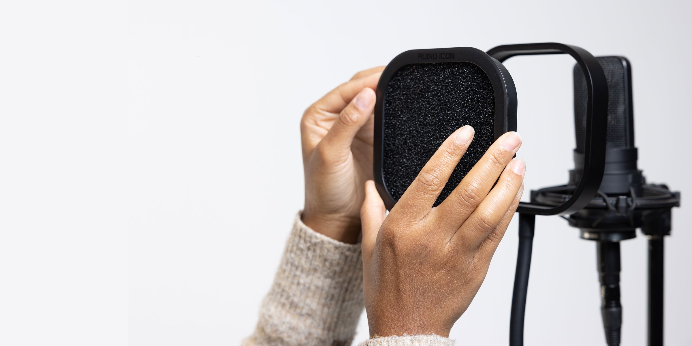 Person placing a acoustic foam microphone pop filter in Flex Pro, against a white background