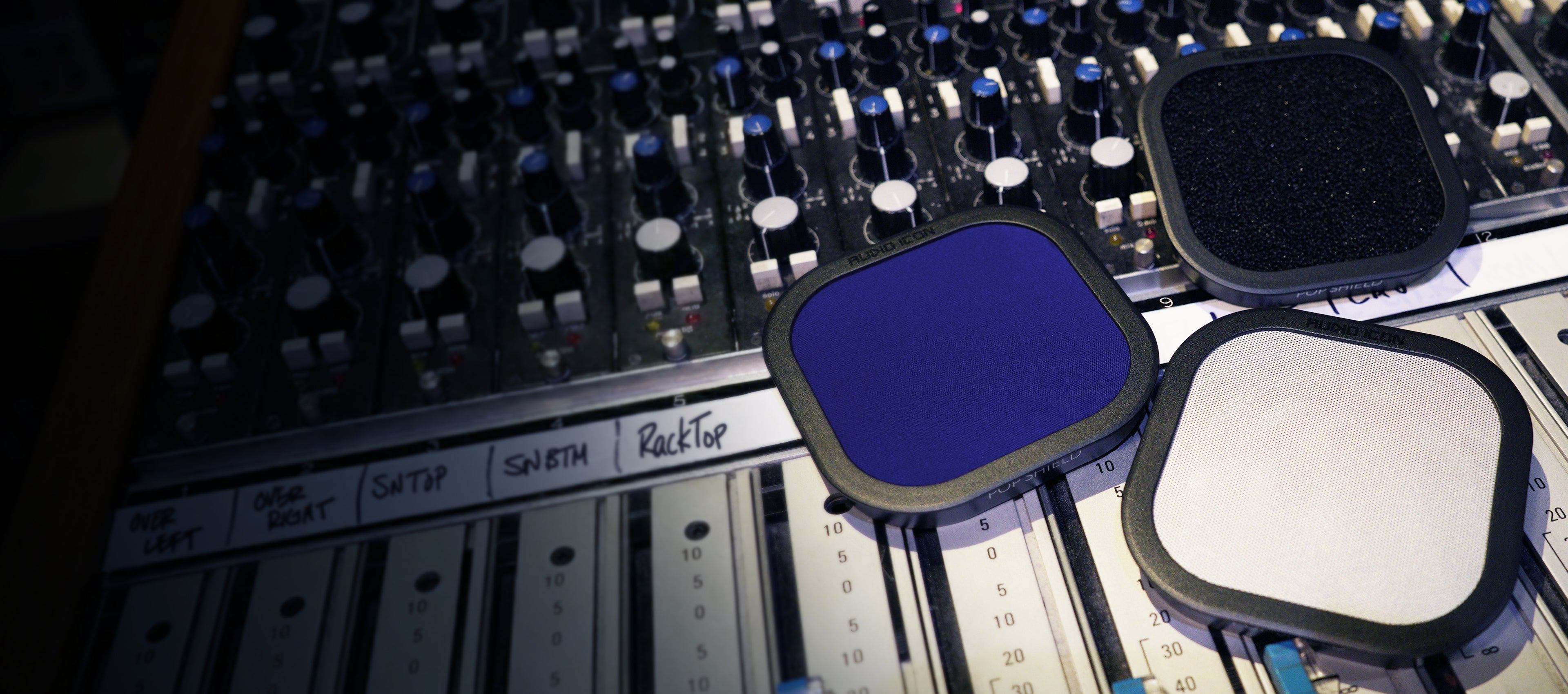 Three Pop Shield Pop filters on a mixing console. Foam, Metal, and Blue Pop Filter