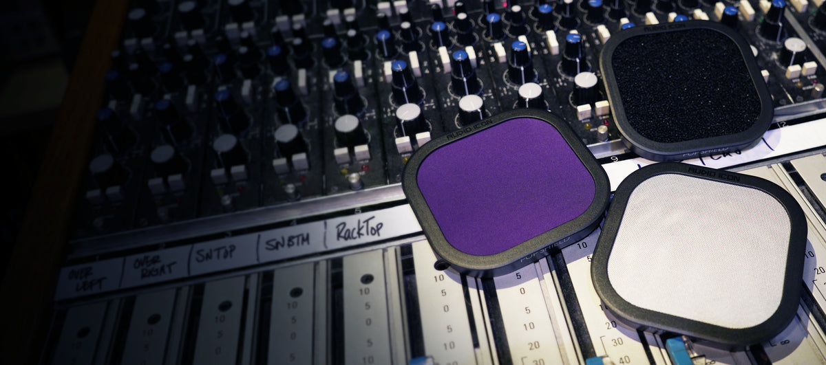 Three Pop Shield Pop filters on a mixing console. Foam, Metal, and Purple Pop Filter