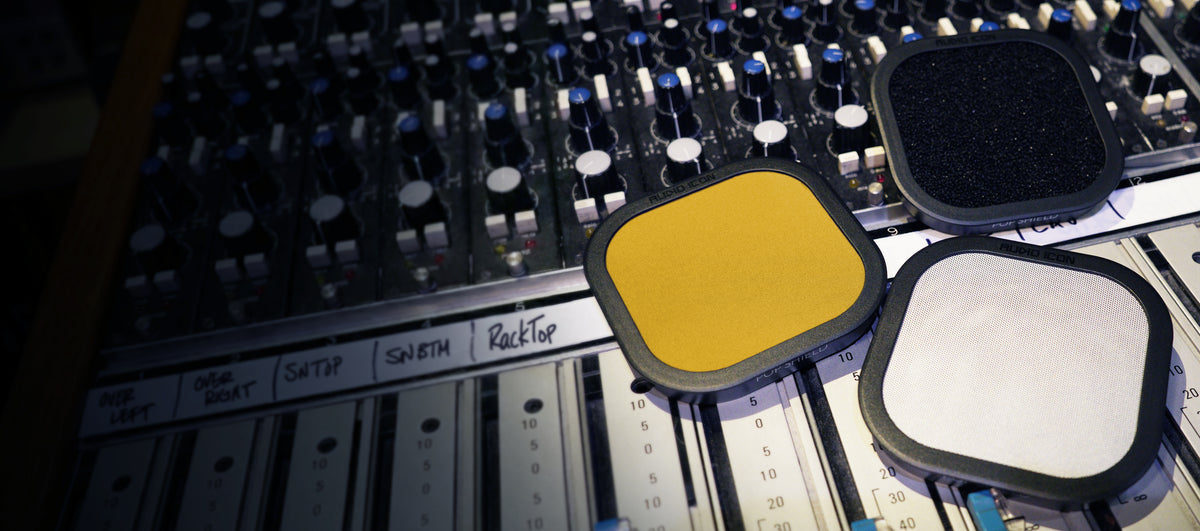 Three Pop Shield Pop filters on a mixing console. Foam, Metal, and Yellow Pop Filter