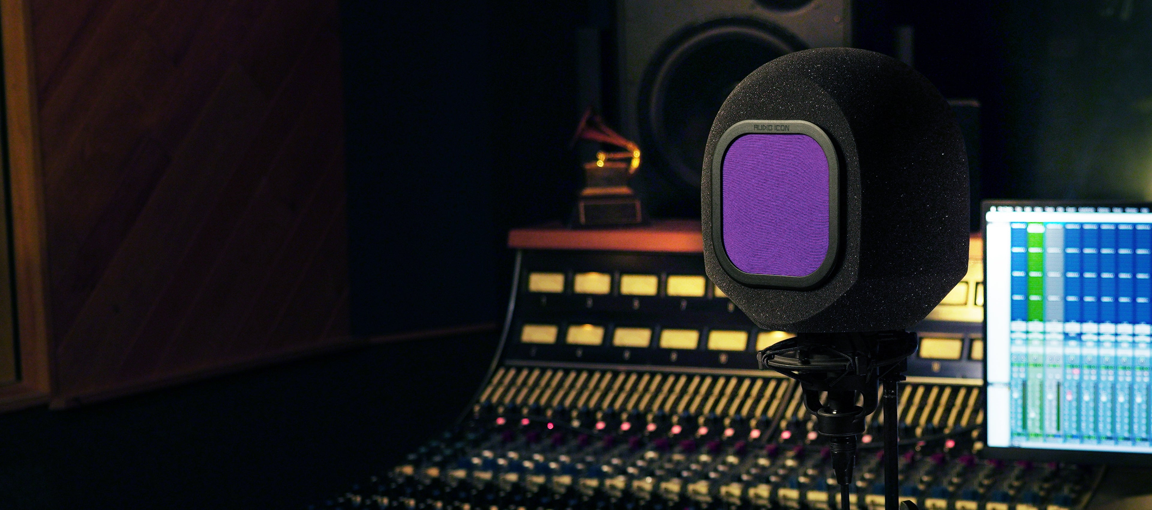 SoundBox Microphone iso booth with a purple pop filter on a mixing console in a dark studio setting.