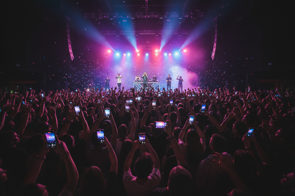Concert with band on stage and audience with phones capturing the moment