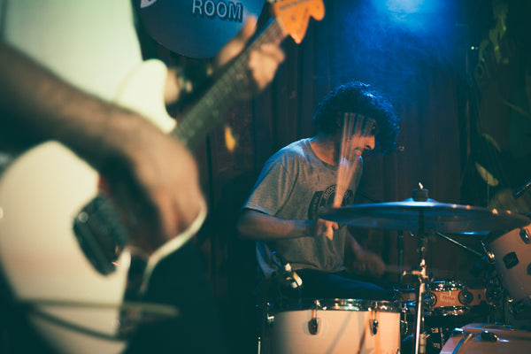 Drummer playing a song in a dark smokey venue with blue light